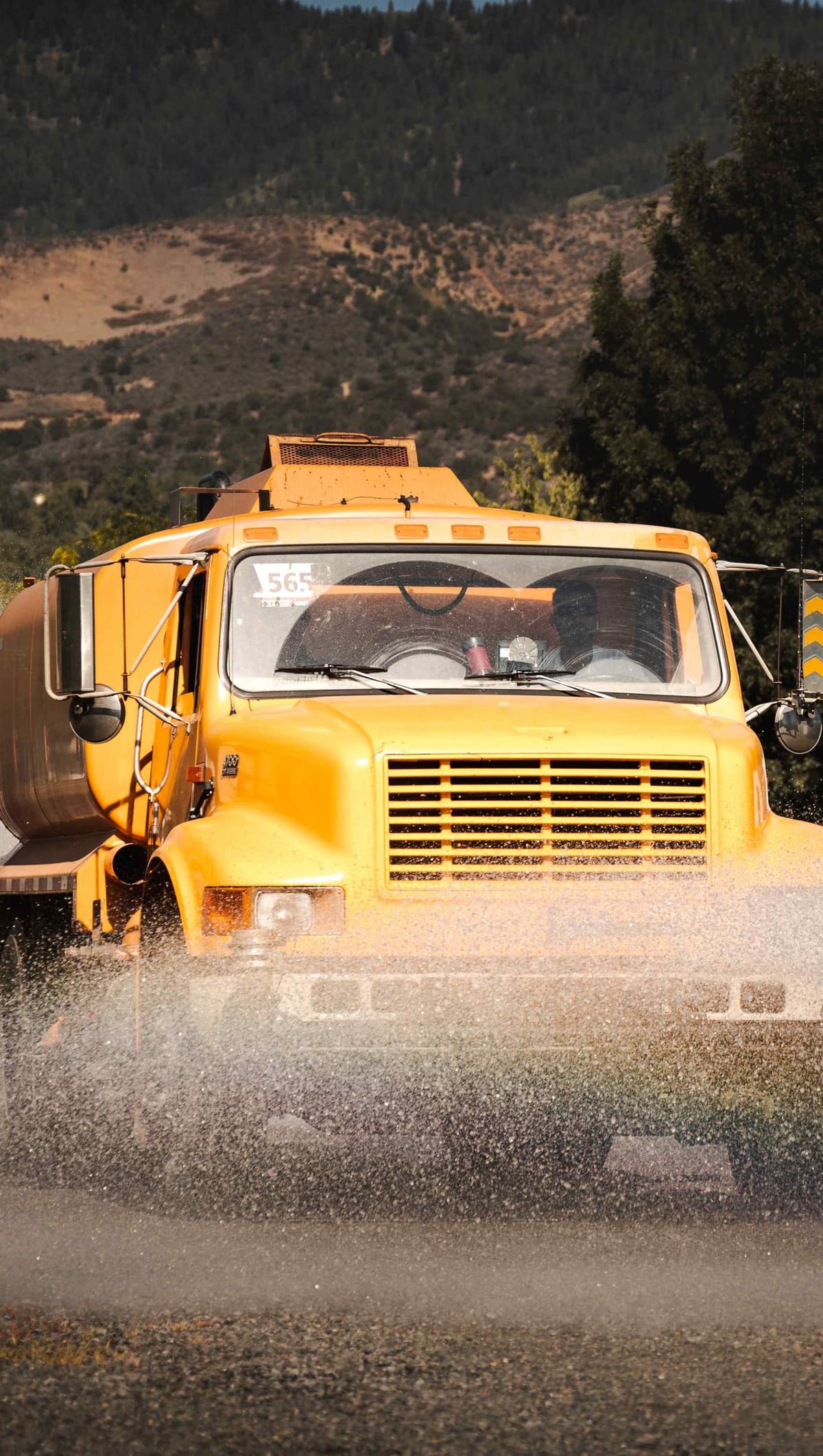 The yellow tanker coming head-on, spraying the gravel in front of it.