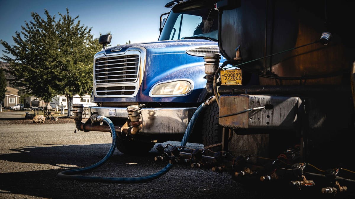 The spray bar and hoses on the front of the blue Freightliner tanker.