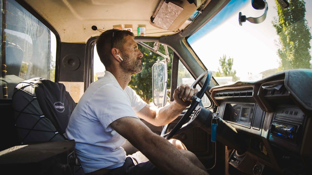 A Rogue Dust Control driver at the wheel inside the truck cab.