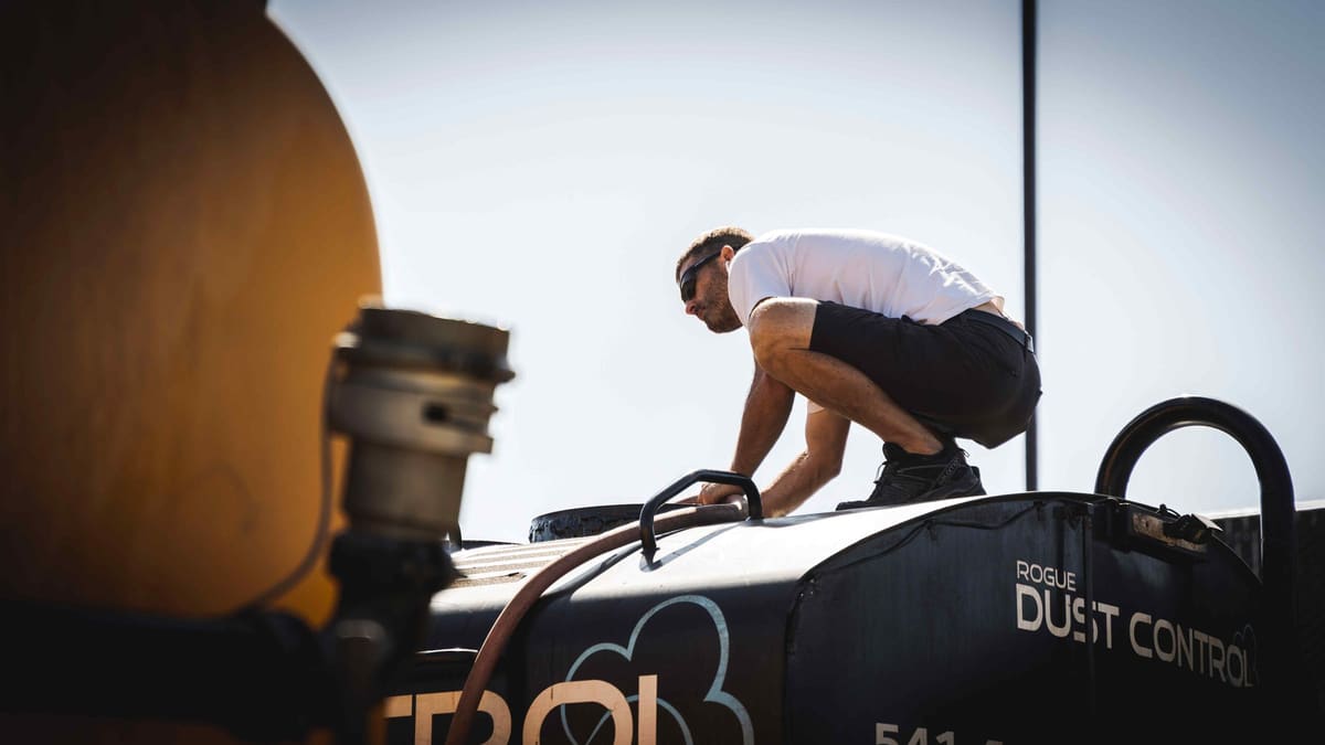 A Rogue Dust Control crew member working on top of the black tank.