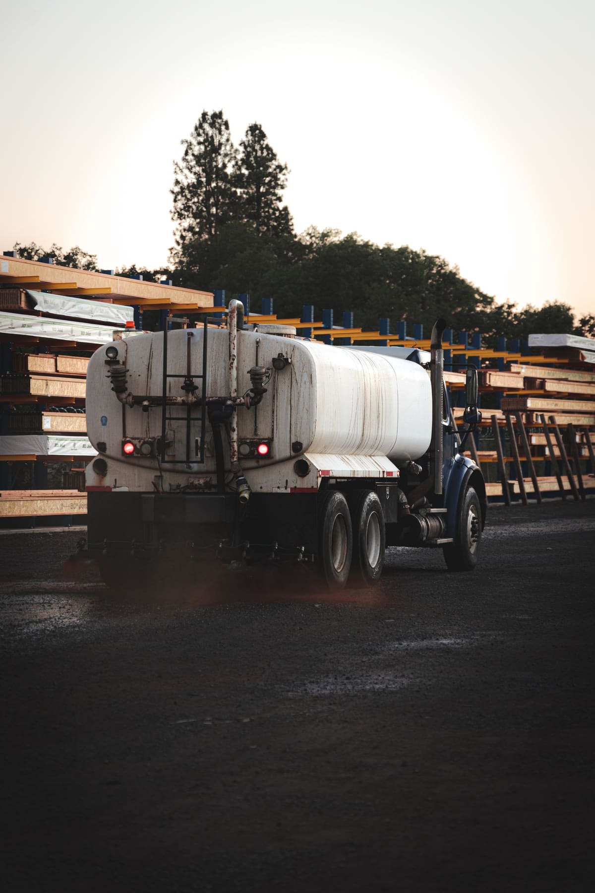 The white tanker driving between lumber racks.